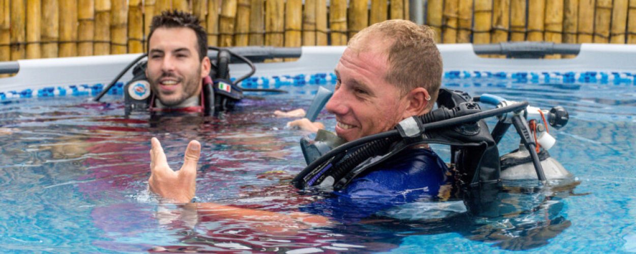 Instructor de buceo dando clase práctica a estudiante en Coveñas